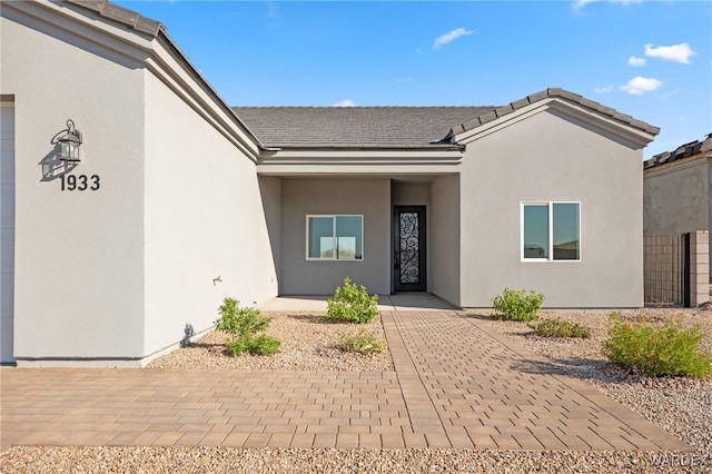 entrance to property featuring a garage and stucco siding