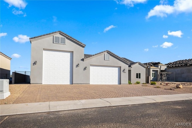 ranch-style house featuring a tiled roof, decorative driveway, an attached garage, and stucco siding