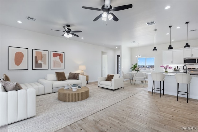 living room featuring light wood-style floors, visible vents, and recessed lighting