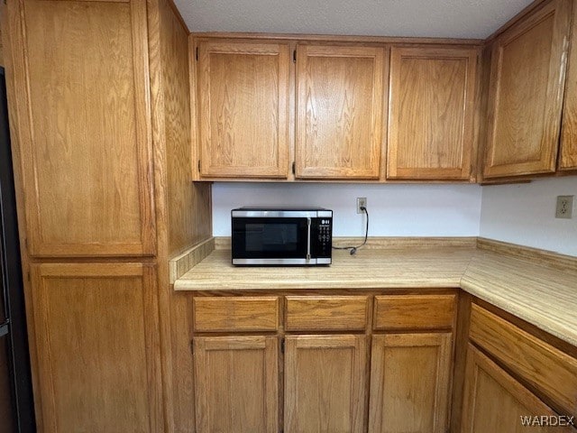 kitchen with brown cabinets, stainless steel microwave, and light countertops