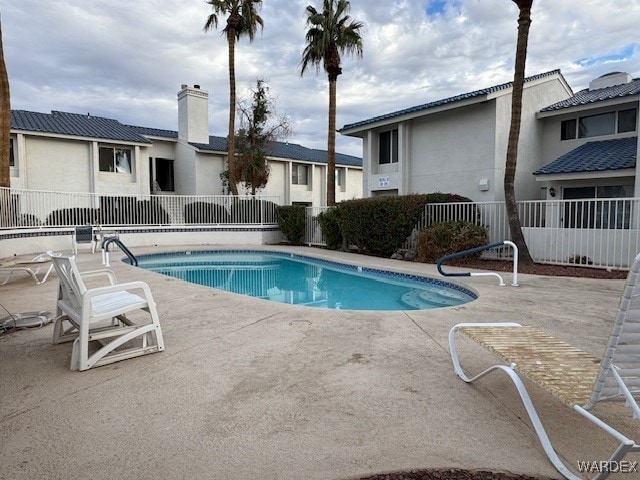 community pool with a patio area and fence