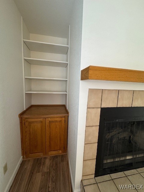 interior space featuring a tiled fireplace, baseboards, and wood finished floors