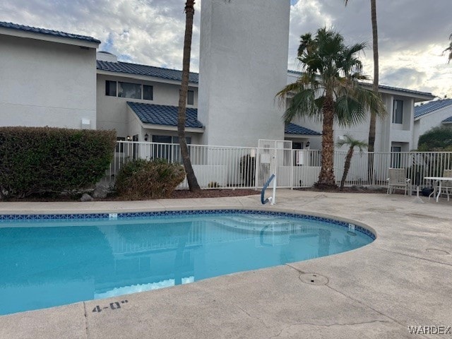 community pool with fence and a patio