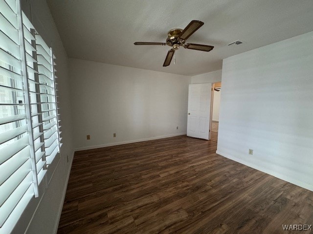 spare room featuring visible vents, dark wood finished floors, a ceiling fan, and baseboards