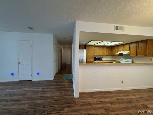 kitchen featuring under cabinet range hood, stainless steel appliances, a peninsula, visible vents, and light countertops