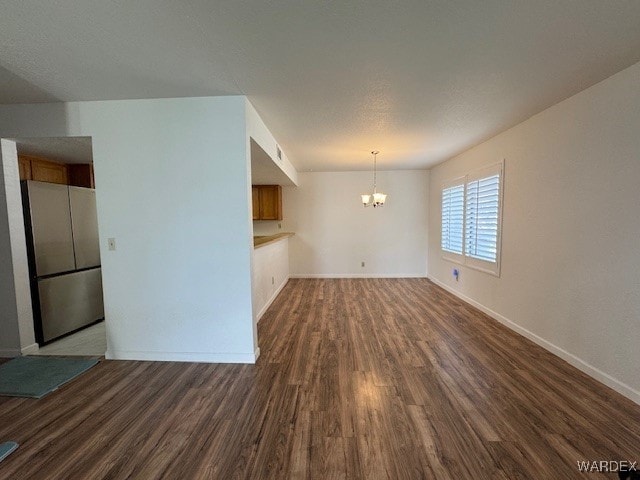 interior space featuring a chandelier, dark wood-style flooring, and baseboards