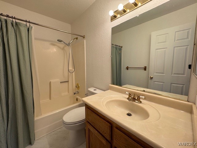 full bath with a textured wall, shower / tub combo with curtain, vanity, and toilet