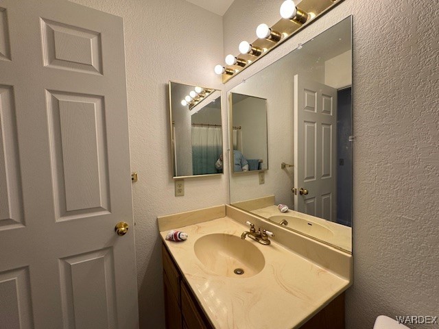 bathroom with a textured wall and vanity