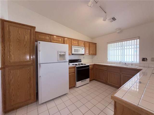 2217 E Emerald River Way, Fort Mohave, AZ 86426 - kitchen with white appliances, tile countertops, track lighting, vaulted ceiling, and brown cabinetry