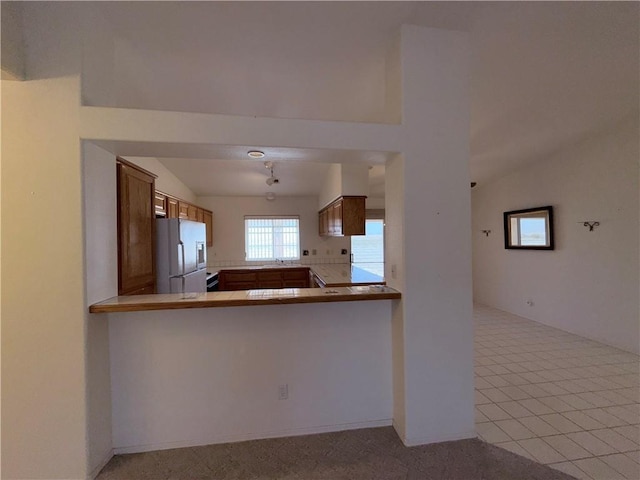 2217 E Emerald River Way, Fort Mohave, AZ 86426 - kitchen with stainless steel refrigerator with ice dispenser, vaulted ceiling, brown cabinets, light countertops, and a peninsula