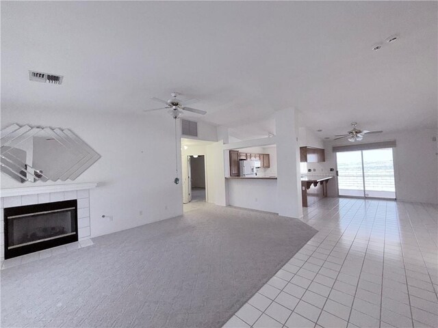 2217 E Emerald River Way, Fort Mohave, AZ 86426 - unfurnished living room featuring a ceiling fan, a tile fireplace, light tile patterned floors, and light carpet