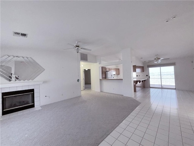 2217 E Emerald River Way, Fort Mohave, AZ 86426 - unfurnished living room featuring a ceiling fan, a tile fireplace, light tile patterned floors, and light carpet