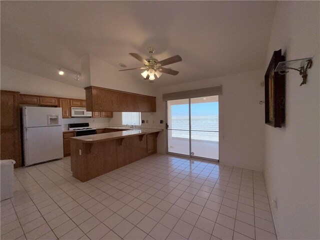 2217 E Emerald River Way, Fort Mohave, AZ 86426 - kitchen with white appliances, a peninsula, lofted ceiling, open floor plan, and light tile patterned floors