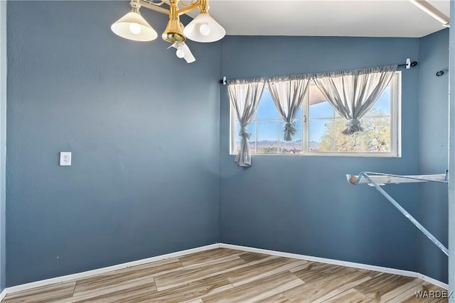 spare room featuring baseboards and wood finished floors