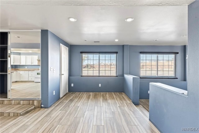 unfurnished room featuring wood finish floors, plenty of natural light, and recessed lighting