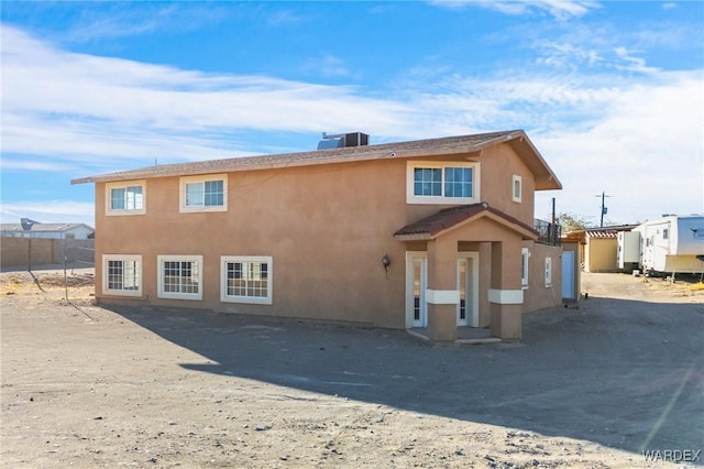 back of property featuring central AC unit, fence, and stucco siding