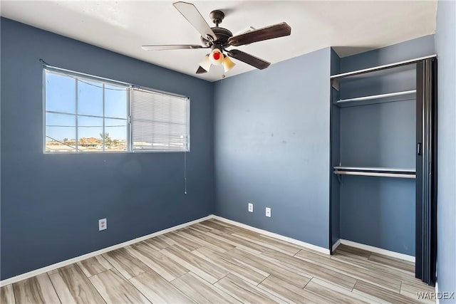 unfurnished bedroom with wood finish floors, a closet, a ceiling fan, and baseboards