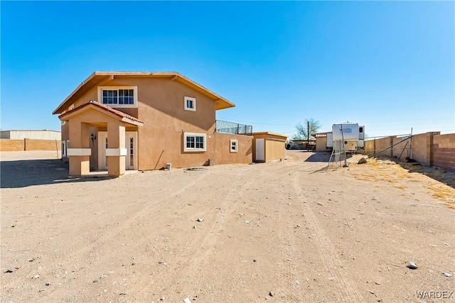 rear view of property with fence and stucco siding