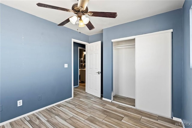 unfurnished bedroom with light wood-style floors, a closet, baseboards, and a ceiling fan