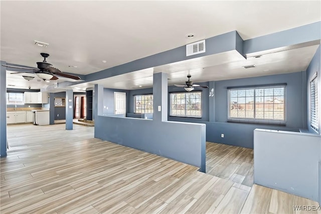 interior space with light wood-style floors, ceiling fan, and visible vents