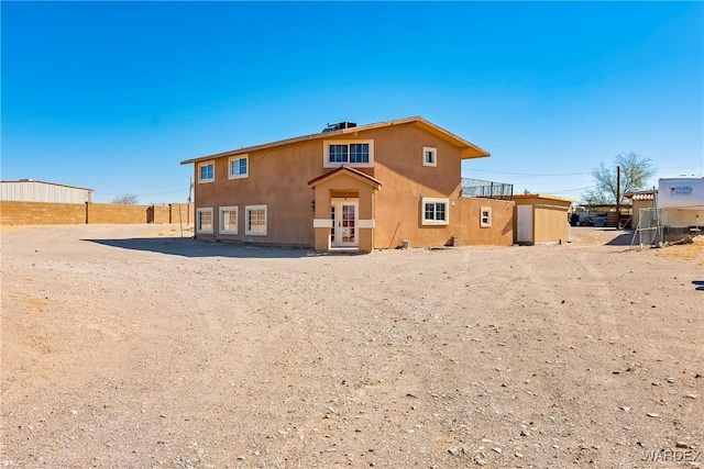 rear view of house featuring fence and stucco siding