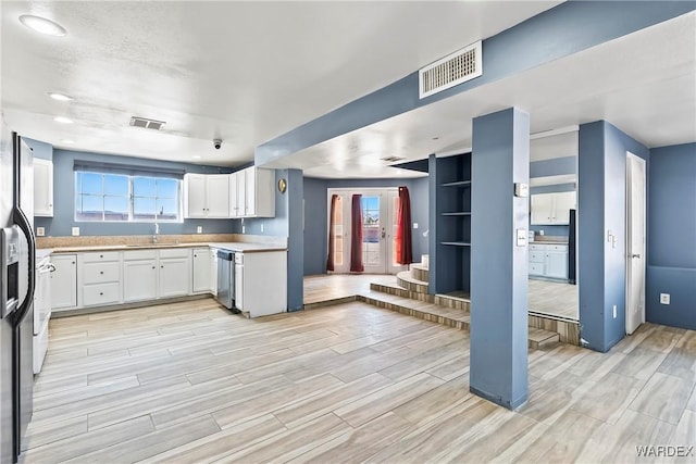 kitchen with visible vents, dishwasher, wood tiled floor, white cabinetry, and a sink