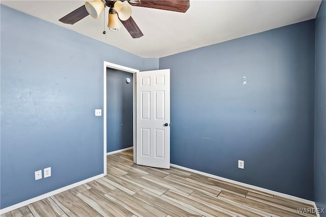 spare room with ceiling fan, wood finished floors, and baseboards