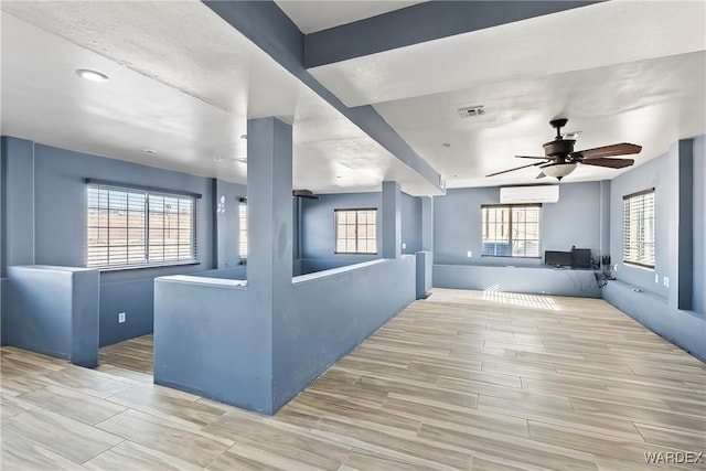 interior space with wood tiled floor, visible vents, ceiling fan, and a wall mounted AC