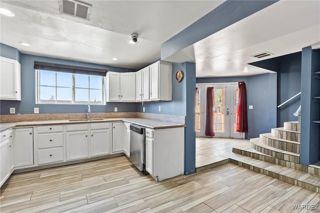 kitchen with a sink, visible vents, white cabinets, and dishwasher