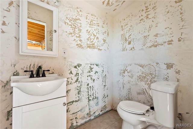 half bathroom with wallpapered walls, vanity, toilet, and tile patterned floors