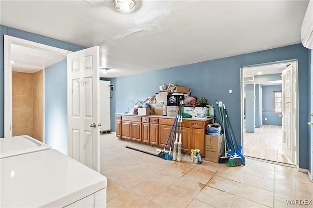 kitchen with light tile patterned floors, light countertops, a wall mounted AC, brown cabinetry, and separate washer and dryer