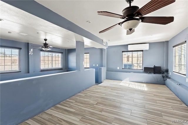 interior space featuring a ceiling fan, wood tiled floor, and a wall mounted air conditioner