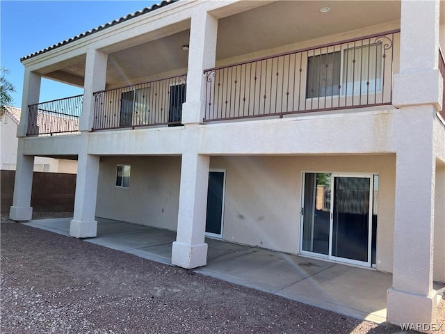 rear view of property featuring a patio, a balcony, and stucco siding