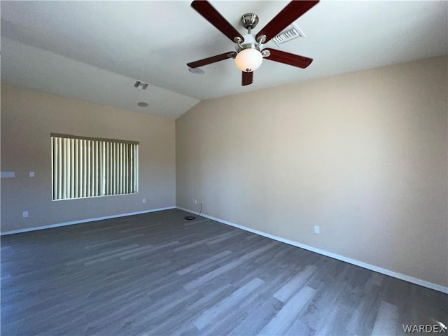 empty room with dark wood-style floors, vaulted ceiling, visible vents, and baseboards