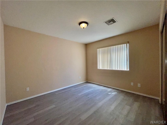 empty room featuring visible vents, baseboards, and wood finished floors