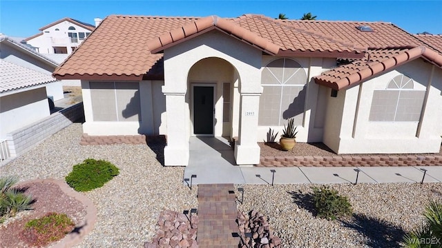 mediterranean / spanish home with a patio, a tile roof, and stucco siding