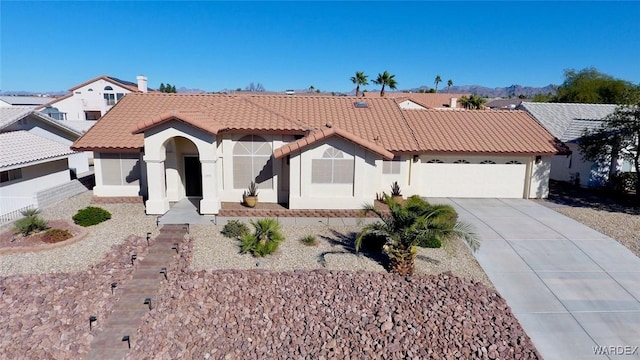 mediterranean / spanish home with a garage, stucco siding, concrete driveway, and a tiled roof