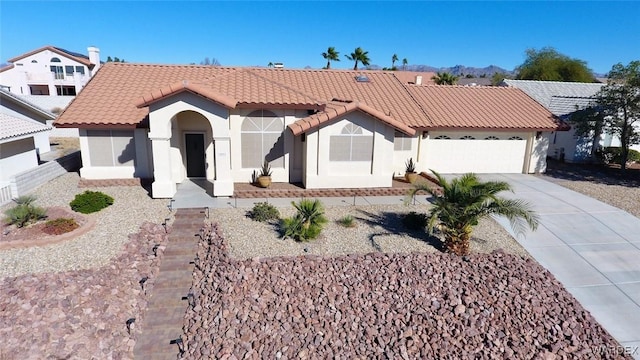 mediterranean / spanish-style home with a garage, driveway, a tile roof, and stucco siding