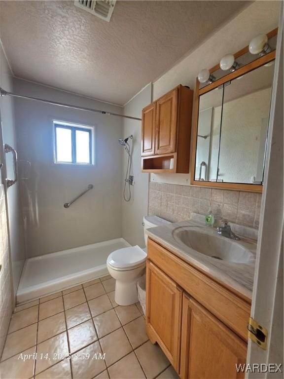 bathroom with visible vents, toilet, a textured ceiling, vanity, and a stall shower