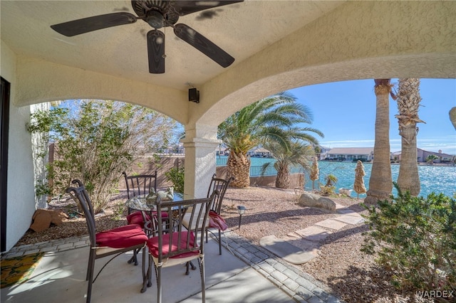 view of patio featuring outdoor dining area, a water view, ceiling fan, and a fenced backyard