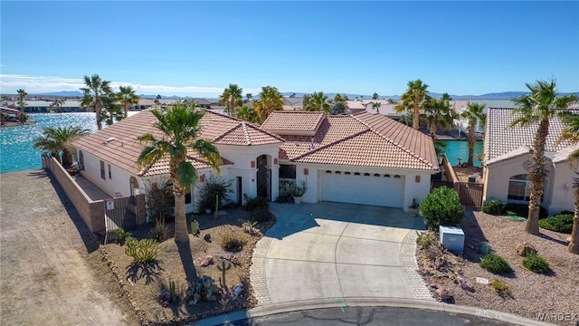 mediterranean / spanish-style home with a water view, driveway, a tiled roof, and stucco siding