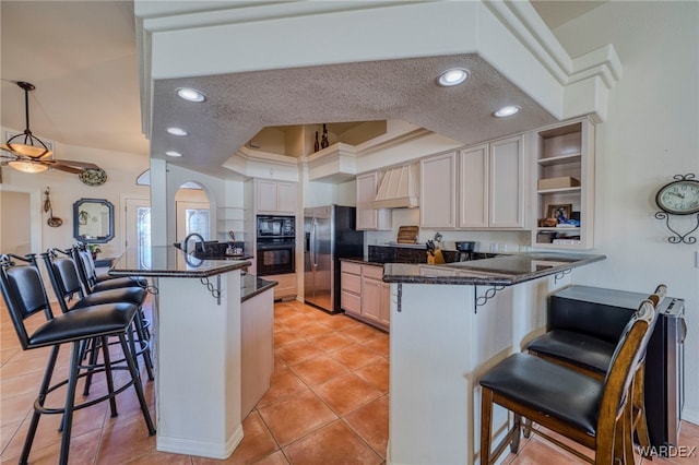 kitchen featuring a breakfast bar, a tray ceiling, a peninsula, and black appliances