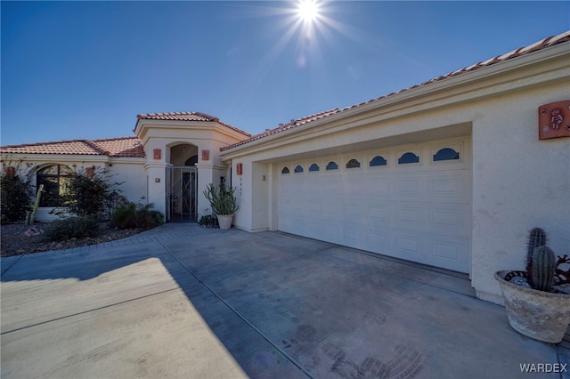 mediterranean / spanish house featuring concrete driveway, an attached garage, a tiled roof, and stucco siding