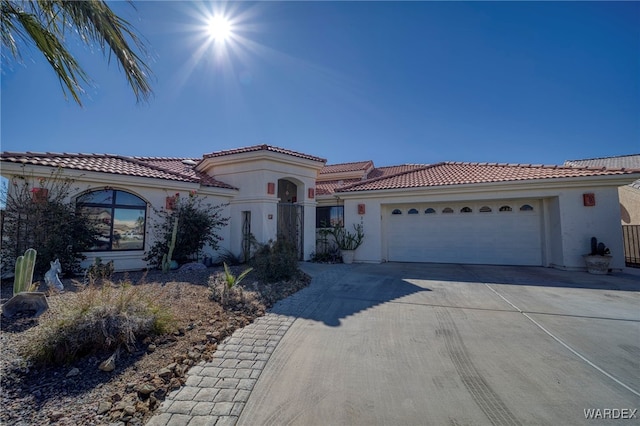 mediterranean / spanish house featuring a garage, driveway, a tile roof, and stucco siding