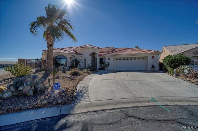 mediterranean / spanish-style home with a tile roof, driveway, an attached garage, and stucco siding