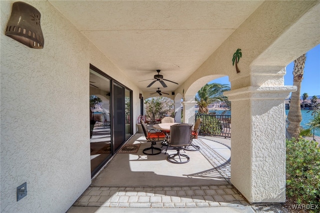 view of patio with outdoor dining space, a water view, and ceiling fan