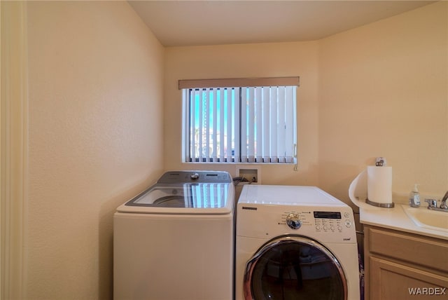 clothes washing area featuring a sink, cabinet space, and washer and dryer