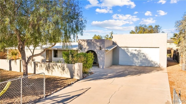 view of front of home featuring driveway, a fenced front yard, an attached garage, and stucco siding