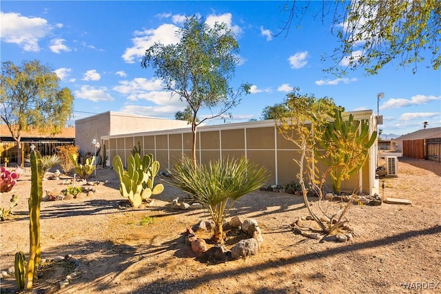 view of side of home featuring cooling unit, fence, and stucco siding