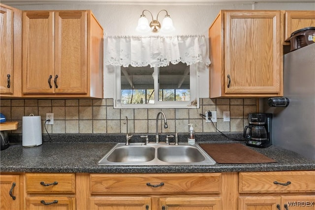 kitchen featuring dark countertops, tasteful backsplash, and a sink